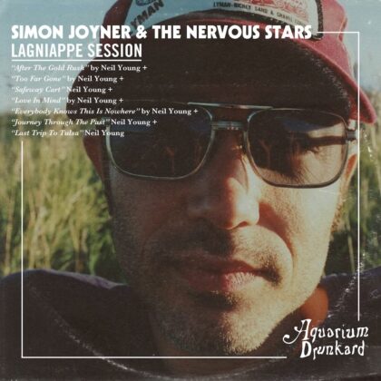 Close-up portrait of a man wearing sunglasses and a red cap, on the album cover 'Simon Joyner & The Nervous Stars – Lagniappe Session' with Aquarium Drunkard logo in the corner.