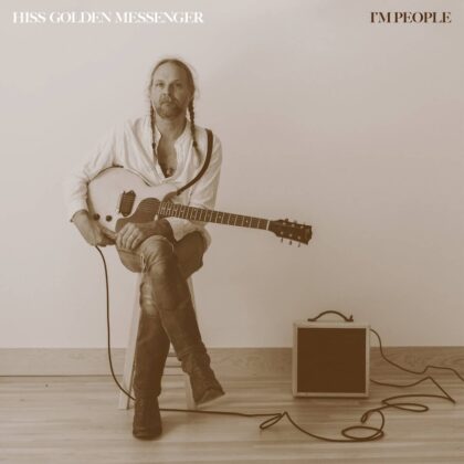 Album cover: a man with long hair and braids sits with a white electric guitar, small amp on the floor beside him.",