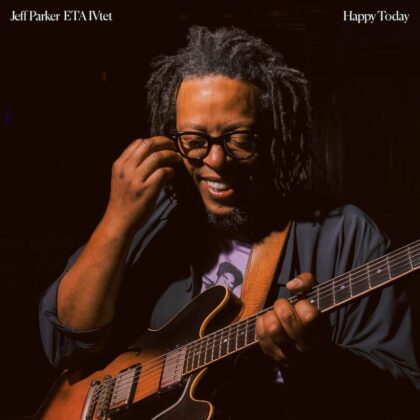 Album cover showing a guitarist with dreadlocks and glasses playing an electric guitar in a dimly lit room; text at the top indicates artist and title.